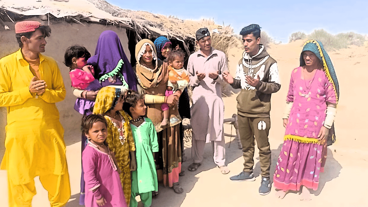 Members of the Marwari tribe, including children and adults, are engaging in a prayer lesson outdoors, their expressions ranging from curious to devout against the modest backdrop of their village.